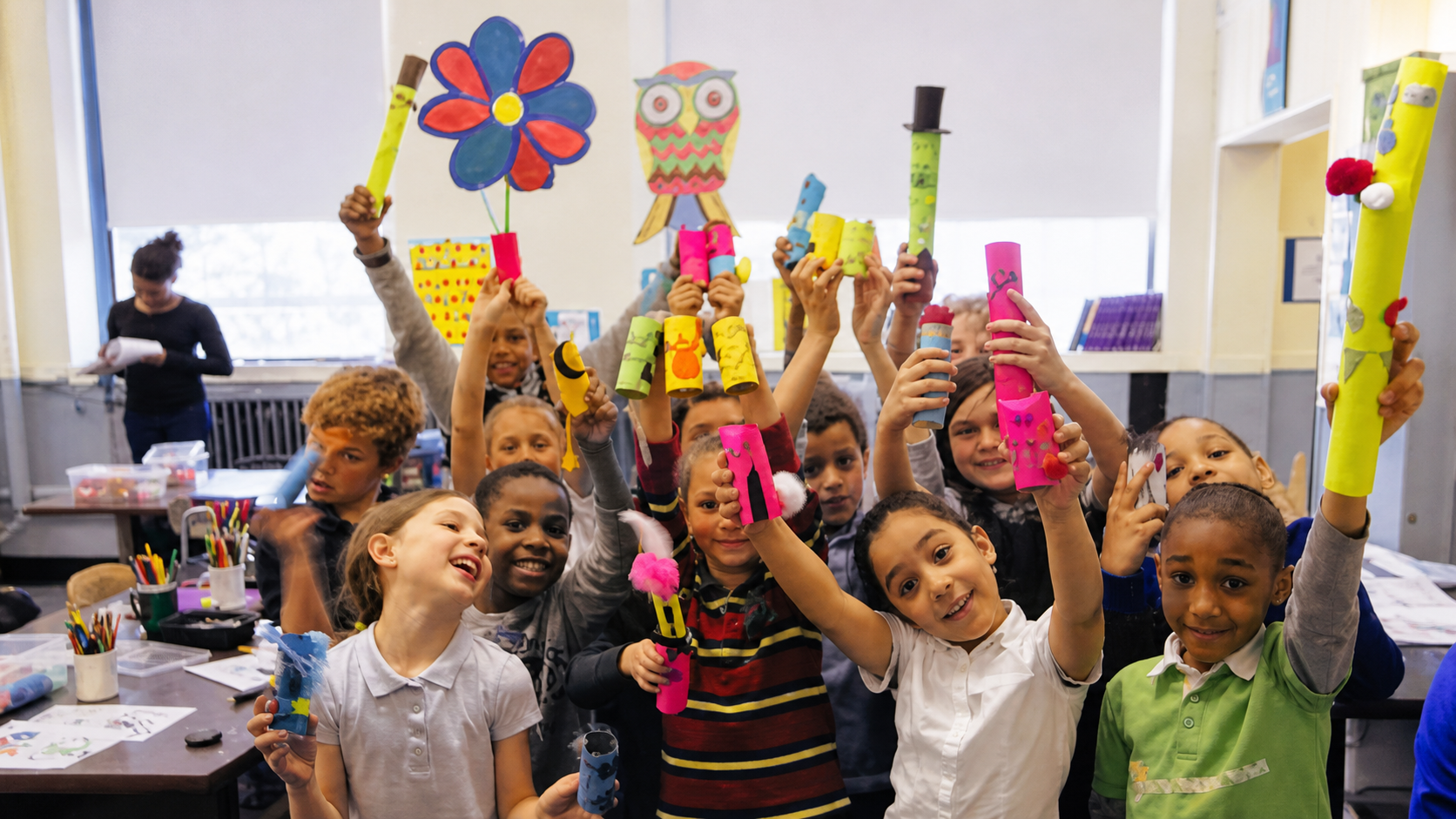 Students celebrating and holding colorful cardboard artworks