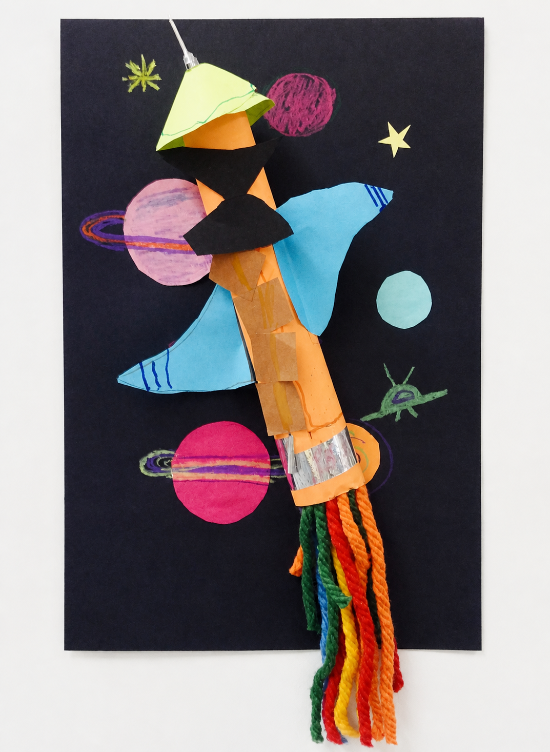 A colorful paper rocket construction displayed against a space scene